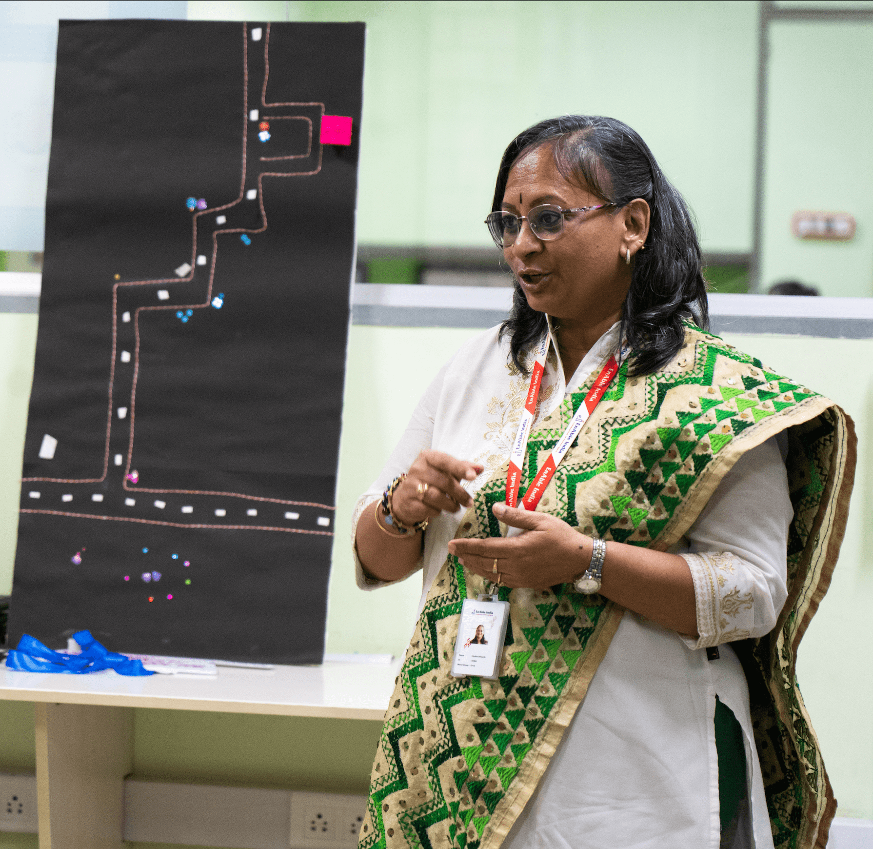 Woman in a green saree presenting near a flowchart board