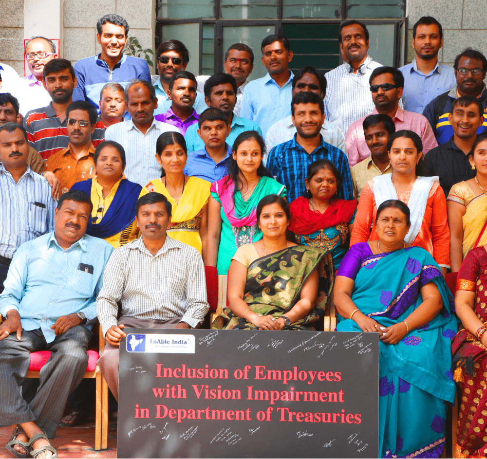 Group photo of employees with visual impairments in front of a banner stating 'Inclusion of Employees with Vision Impairment in Department of Treasuries'